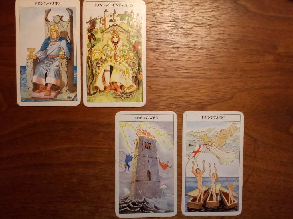 Four tarot cards are laid out on a table: the King of Cups, the King of Pentacles, the Tower and Judgement.